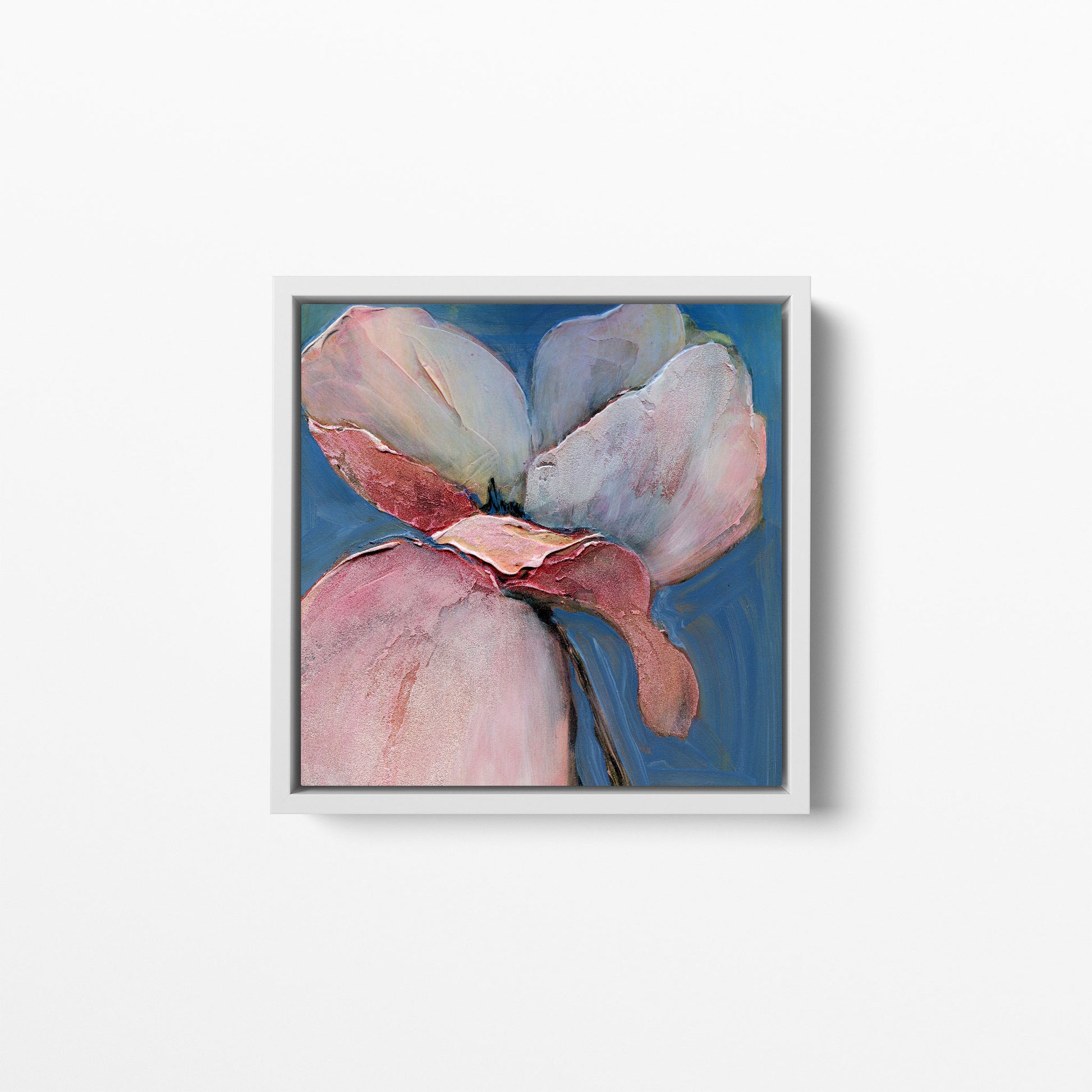 A 12x12 inch print of an acrylic painting of a poppy flower with soft blues and pink/peach hues. Framed in a white wood frame.